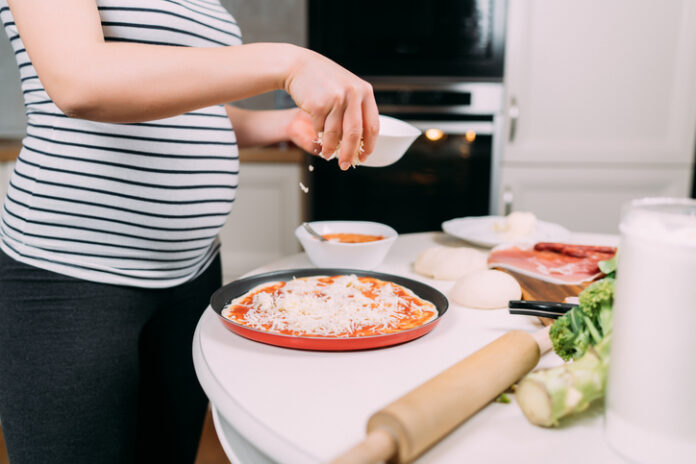 close up details of pregnant woman making home pizza