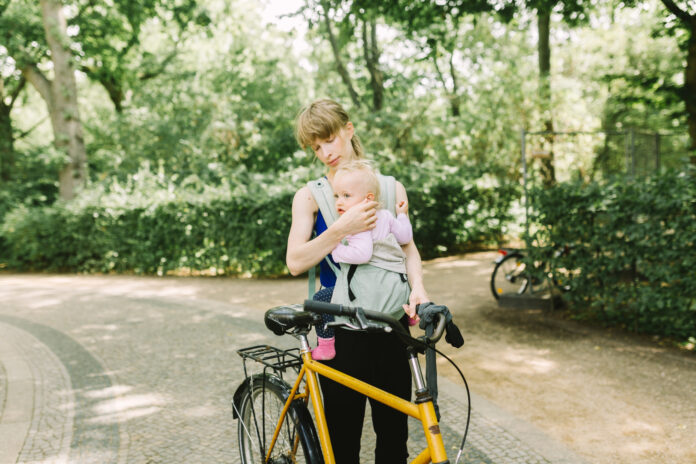 Young mother commuting with her baby through the park