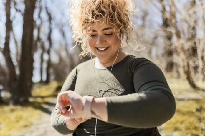 Young overweight woman runner with headphones looking at smart