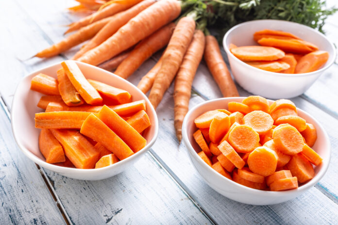 Fresh carrot and carrots slices on table