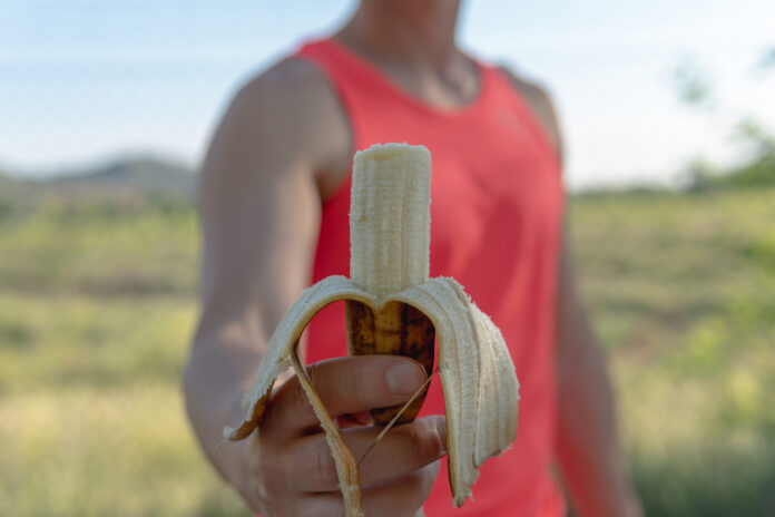 Athlete man showing a banana that is bitten